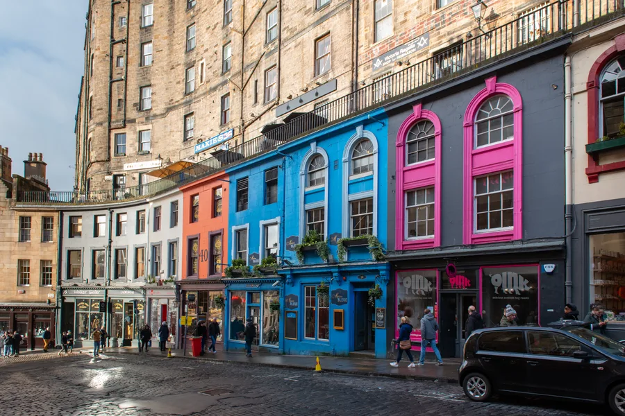 A row of brightly colored shopfronts on a historic Edinburgh street