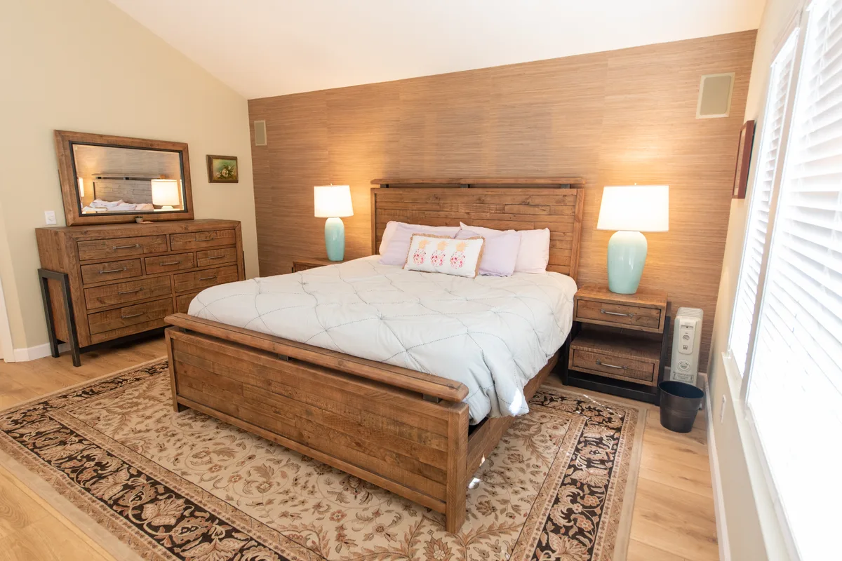 Master bedroom with a wood bed frame and warm lamplight