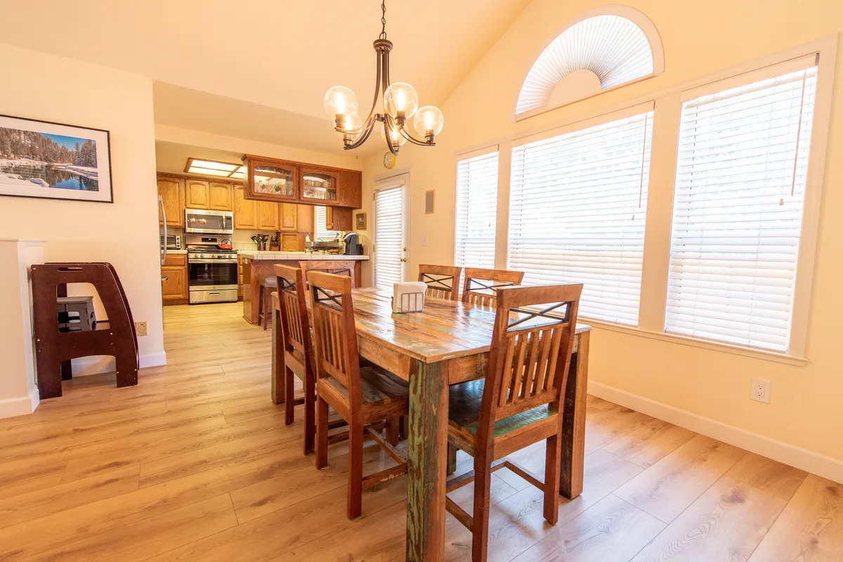 Dining table for six beside sunny windows, open to the kitchen