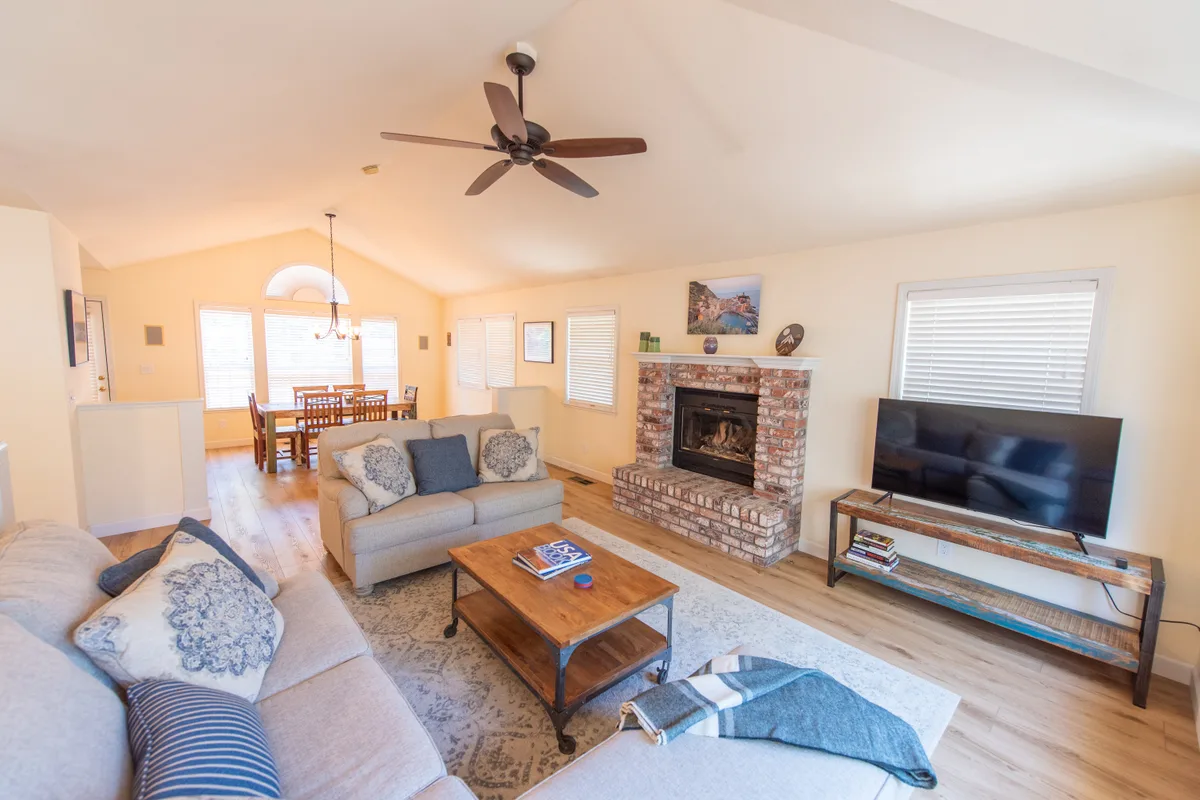 Open great room with a brick fireplace, sofas, and the dining area beyond